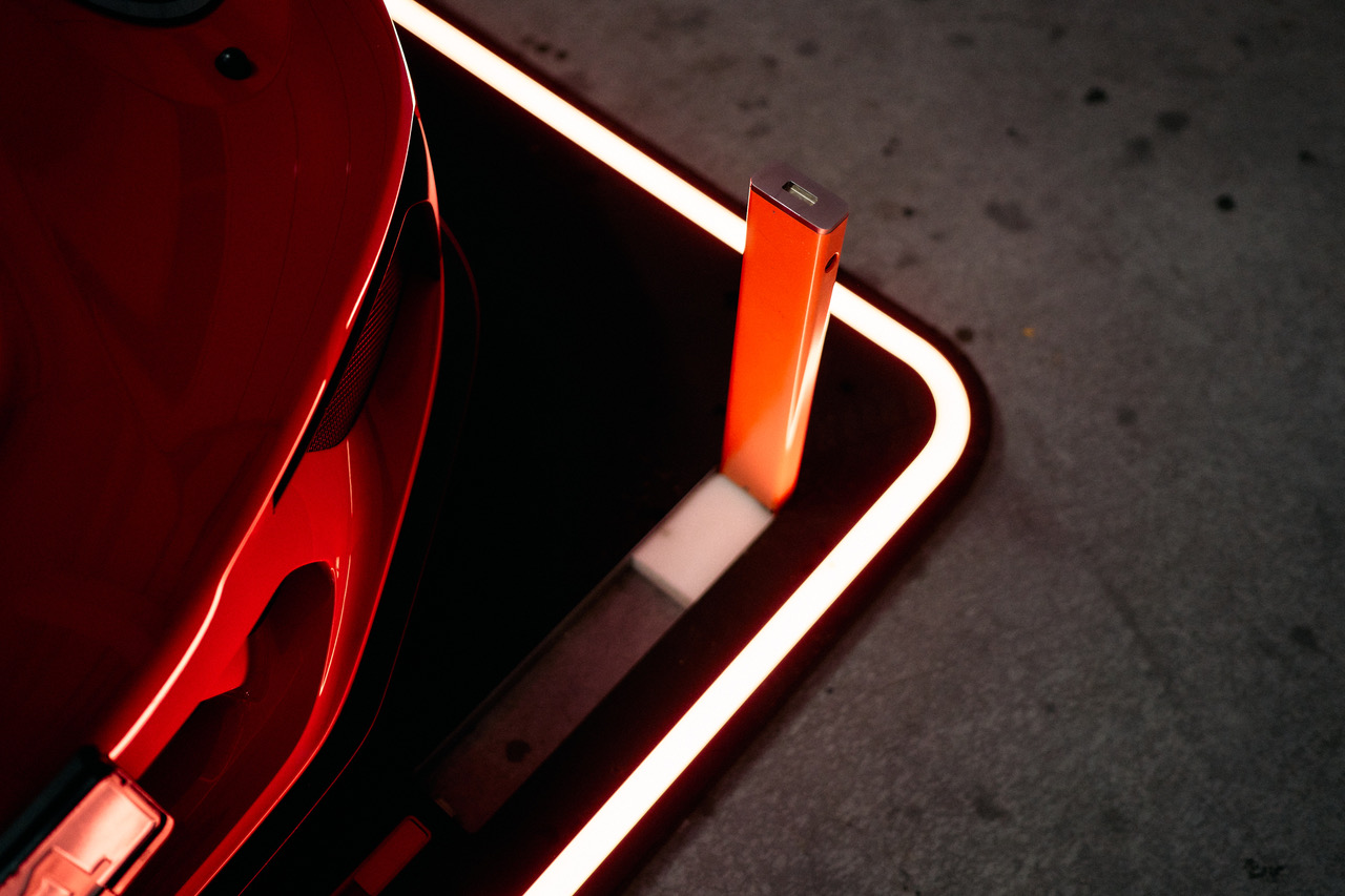 Illuminated GuardPad bolt raised next to a red sports car